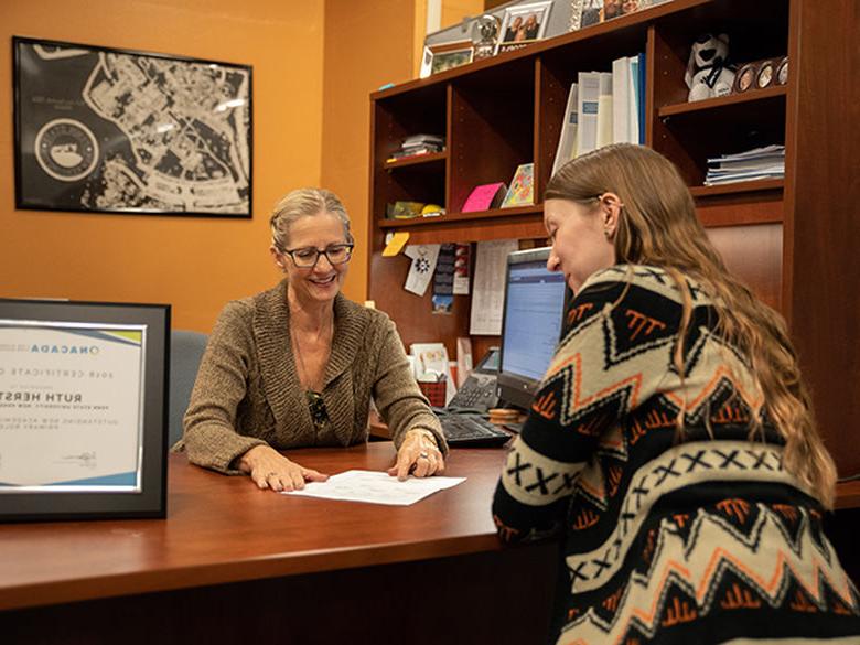 A female student meets with her academic adviser to discuss her course schedule